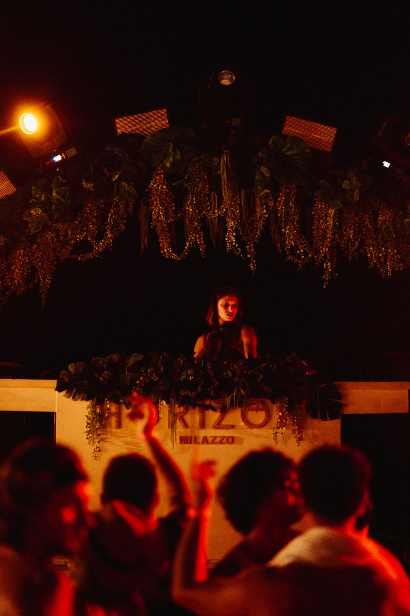 DJ performing under a botanical canopy at Horizon Beach Club, Milazzo, HORIZON MILAZZO signage visible