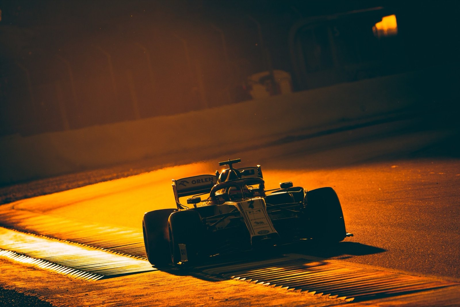 A Formula 1 car crossing the kerb in low backlit sun at pre-season testing, Circuit de Barcelona-Catalunya, 2020