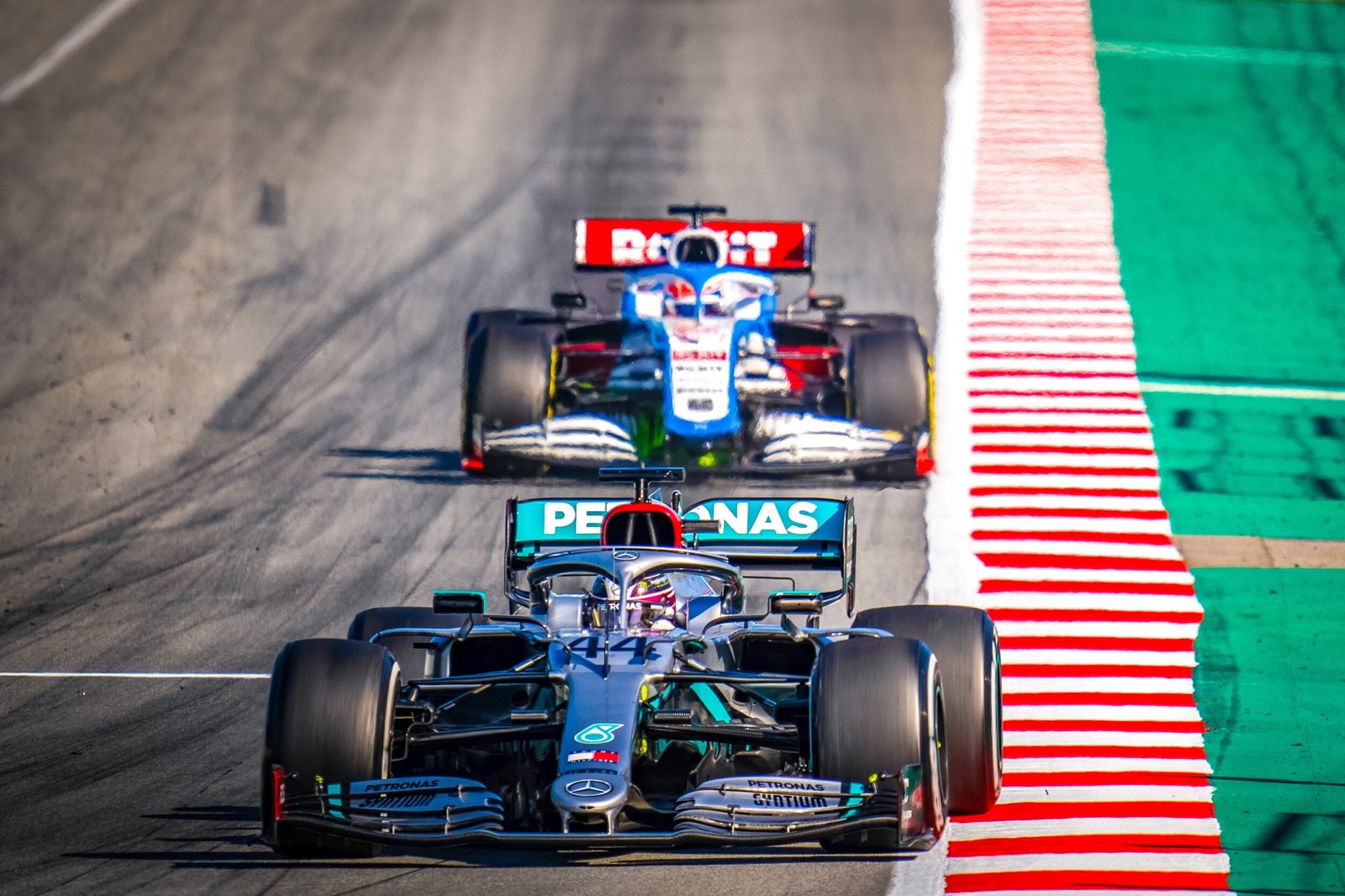 Mercedes W11 number 44 leading a Williams FW43 through the green and red kerbs at Formula 1 pre-season testing, Barcelona 2020
