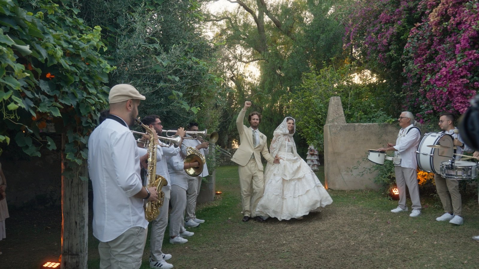 Una banda di ottoni accompagna Lucrezia e Giulio attraverso il giardino al loro destination wedding in Sicilia, 2023