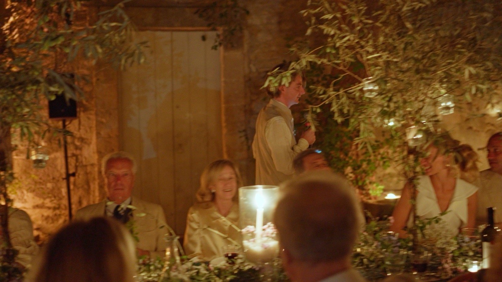 A guest giving a candlelit speech at the reception dinner table