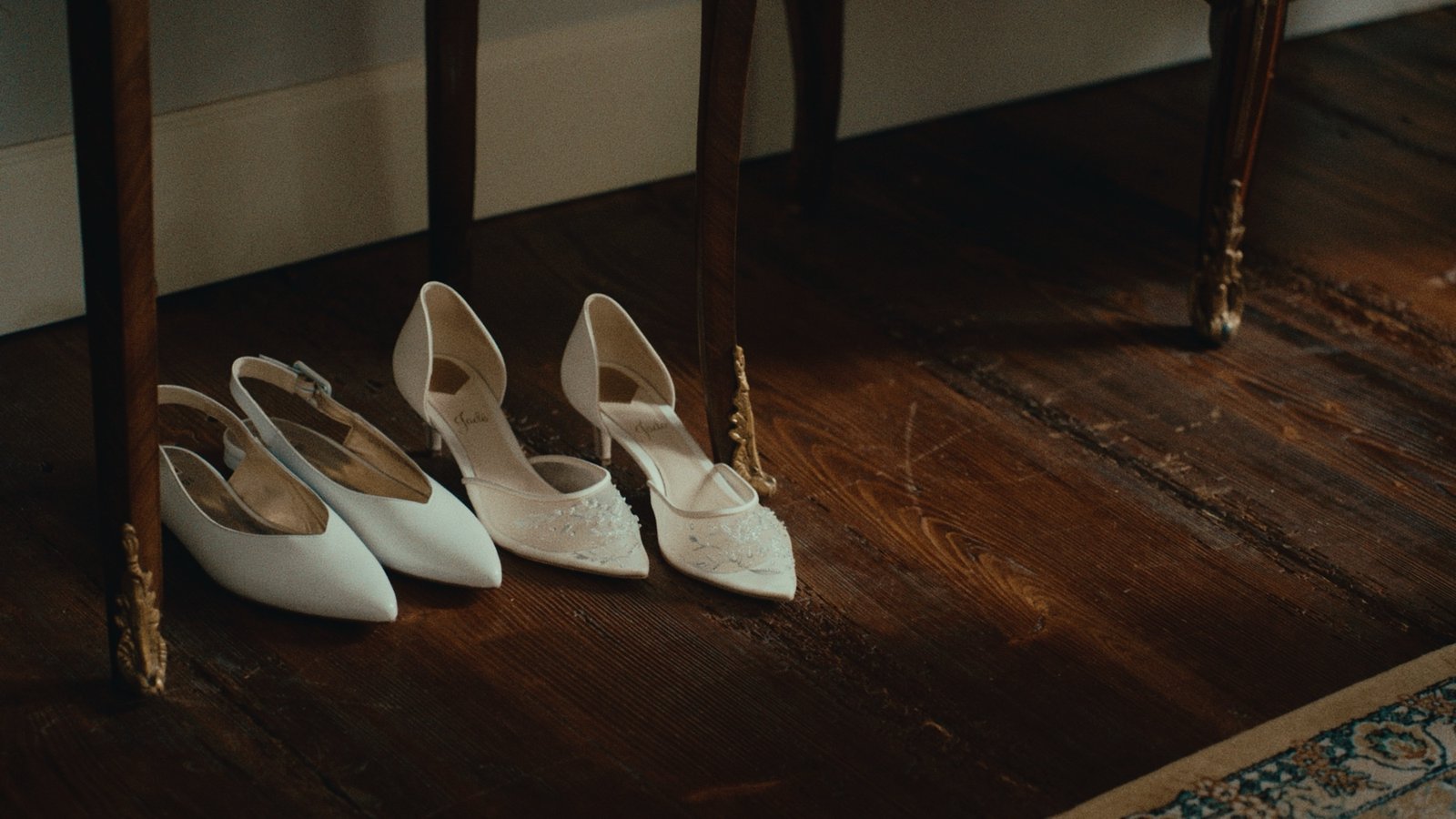 Due paia di scarpe da sposa bianche sul parquet della stanza dei preparativi
