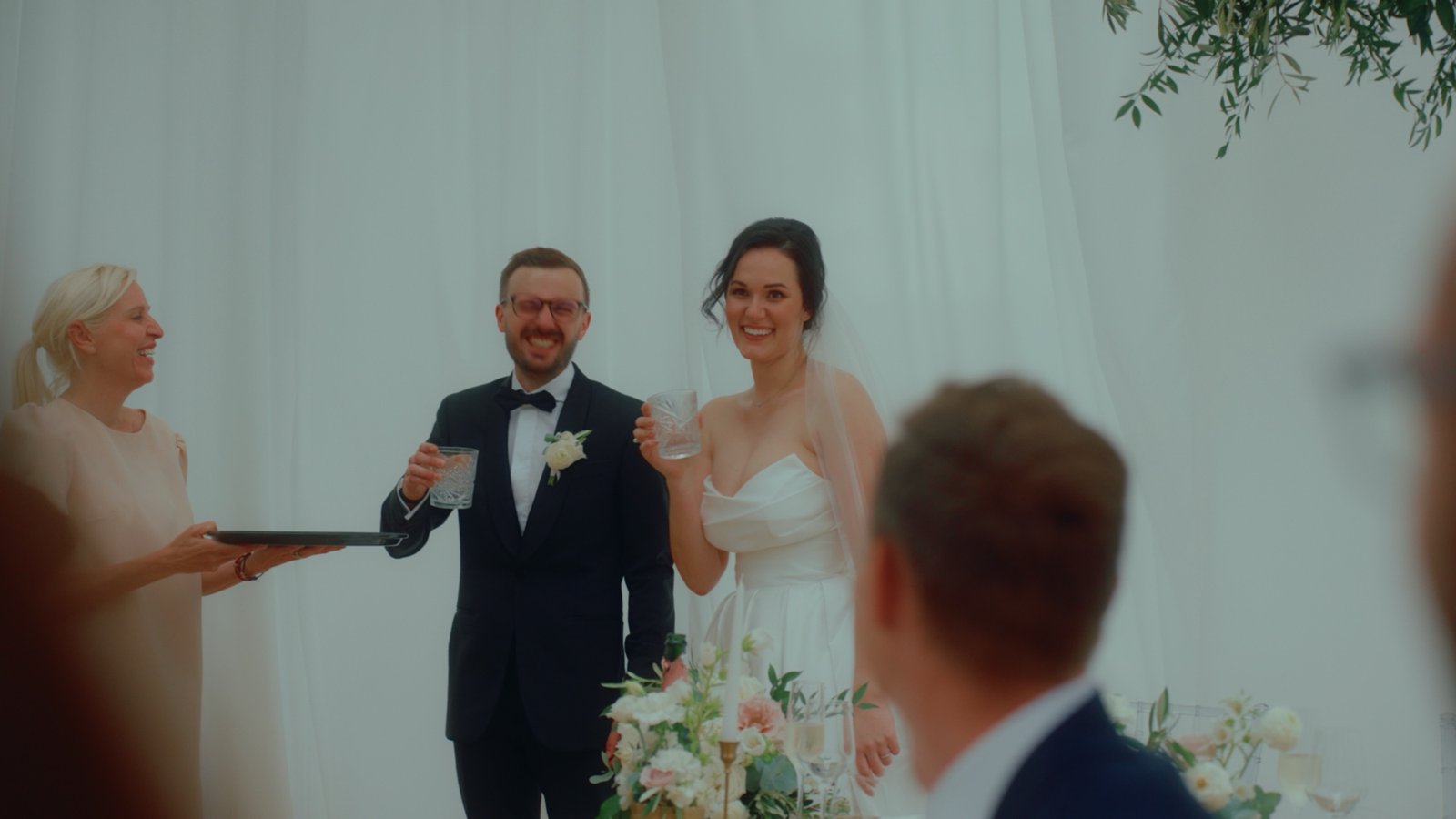 Gli sposi durante la cerimonia sotto un drappo bianco, con l'officiante che legge accanto a loro