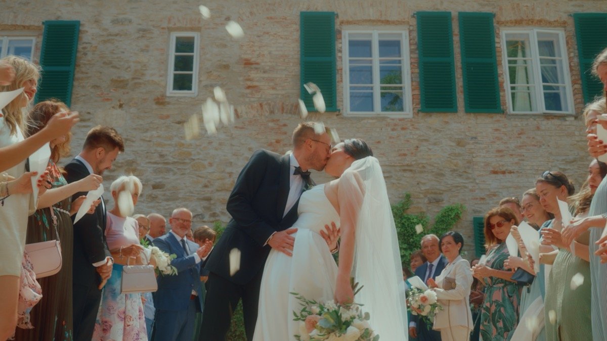 The newlyweds kissing under a shower of confetti thrown by guests outside the venue