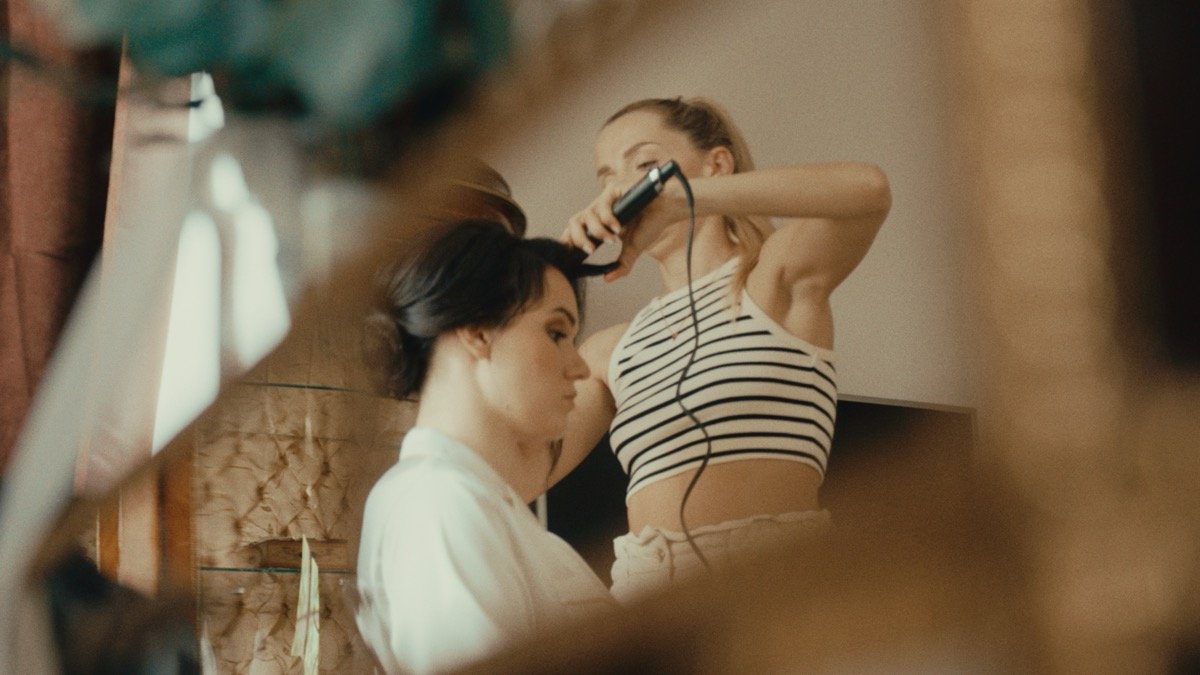 Bride having her hair styled in a mirror before the ceremony