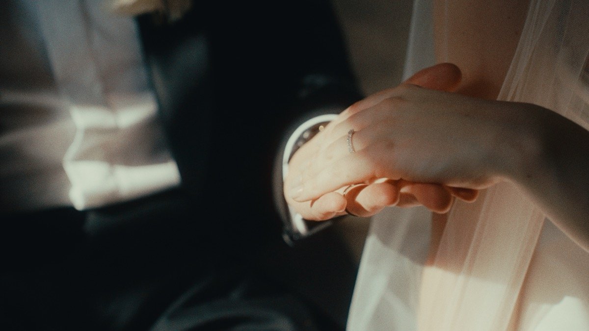 Close-up of the newlyweds' hands together, showing the wedding rings