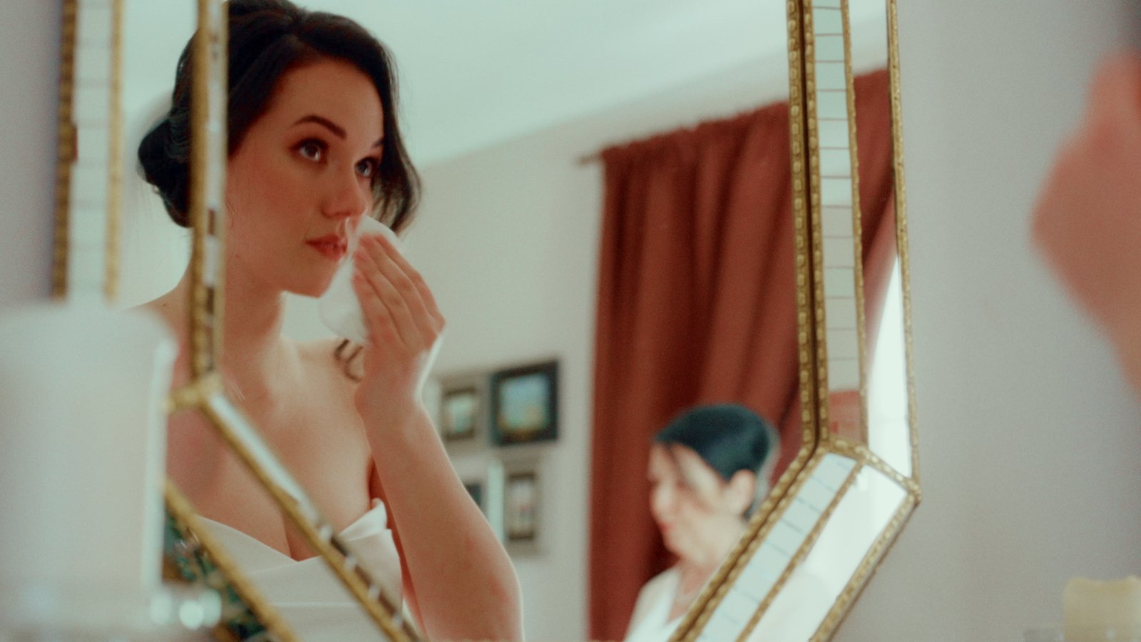 Bride having her hair styled in front of a vintage mirror before the ceremony