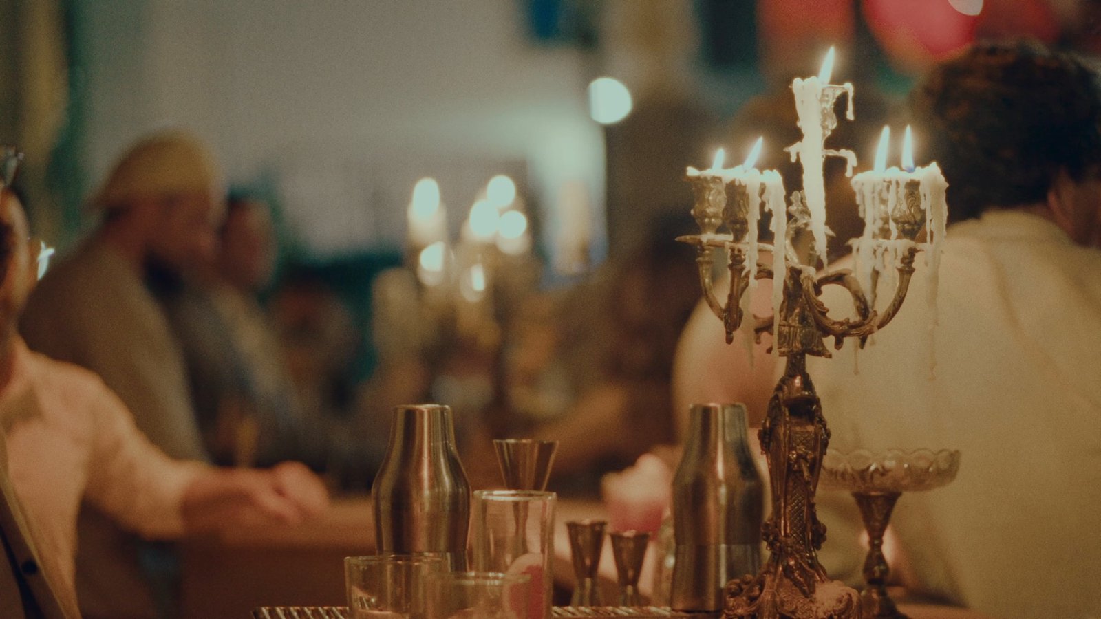 A silver candelabra, glasses and bottles on a reception table lit by candlelight