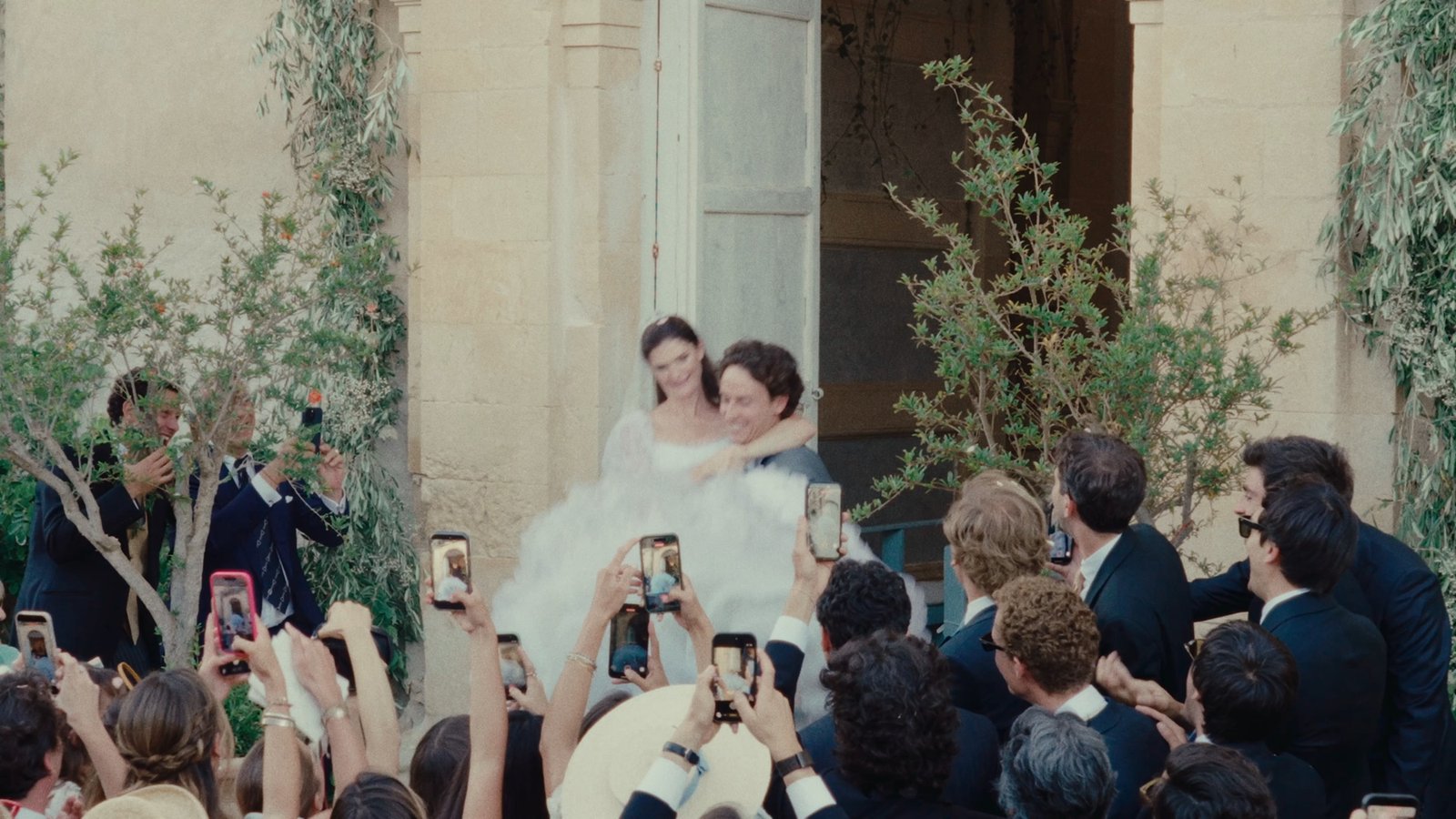 Guests raising their phones as the couple come out to meet them after the ceremony