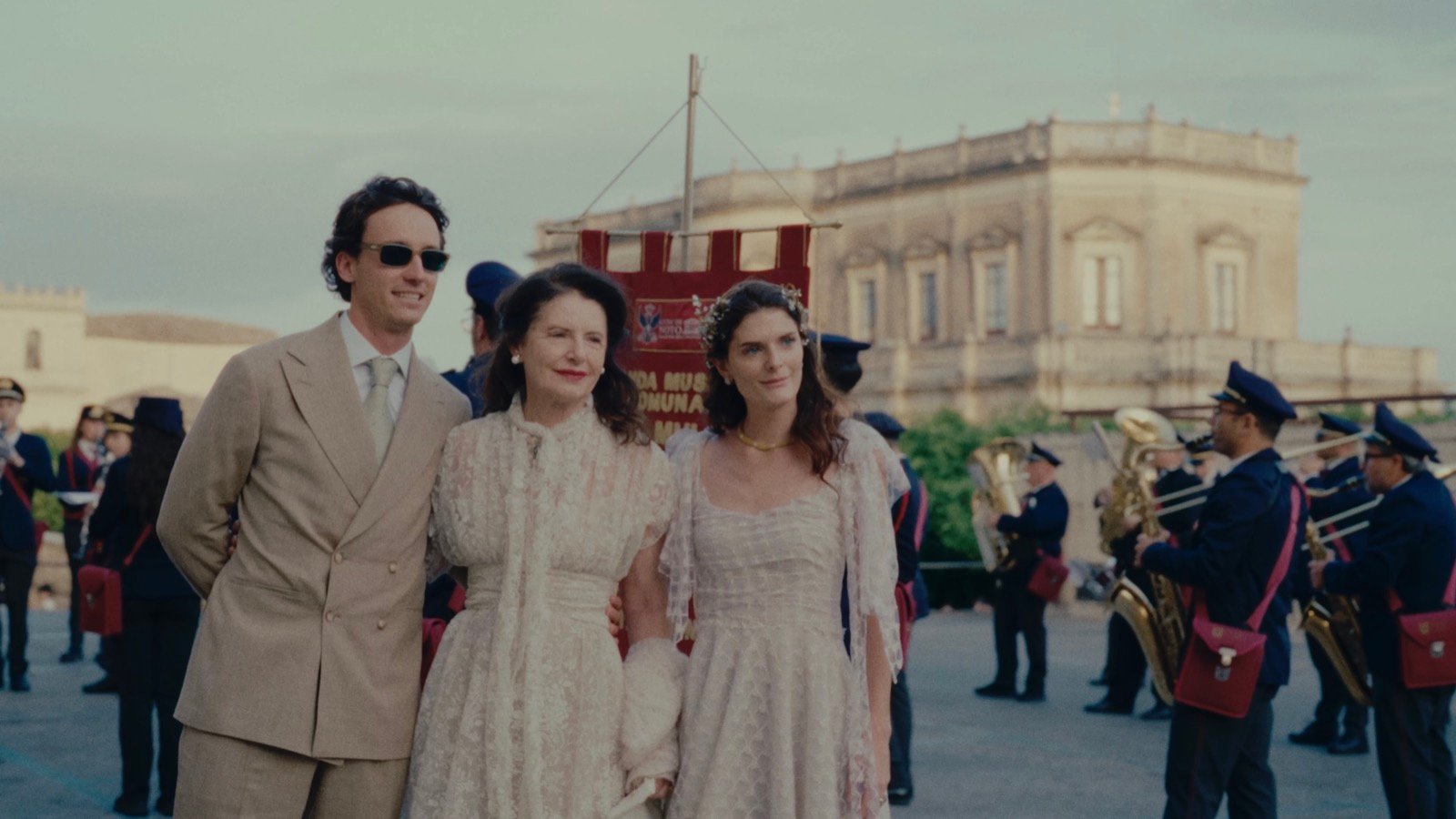 The groom, his mother and the bride together in Noto's main square, with a marching band behind them