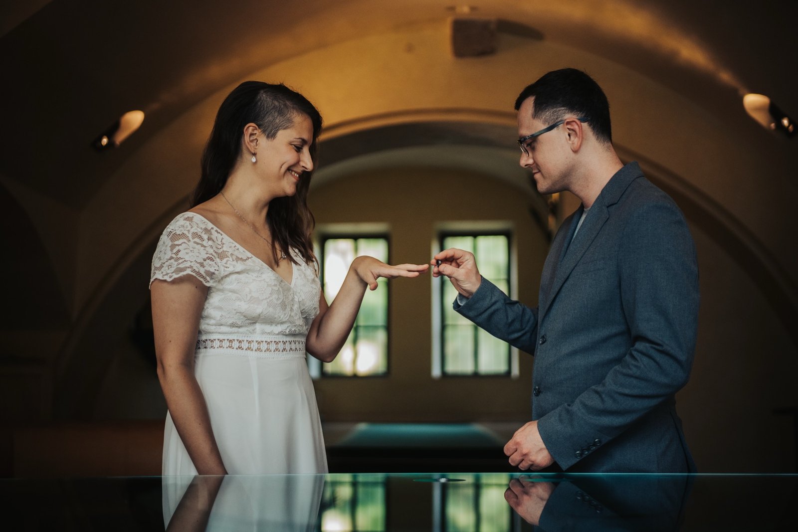 Bride and groom exchanging rings inside a vaulted stone ceremony room in Prague