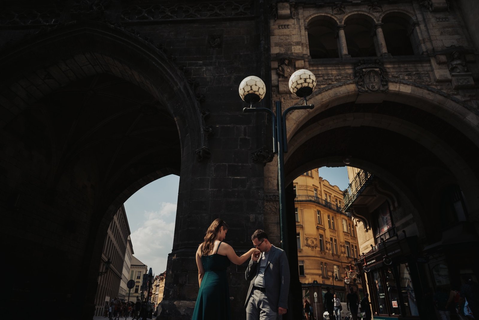 Couple sharing a quiet moment beneath a stone archway in Prague's Old Town