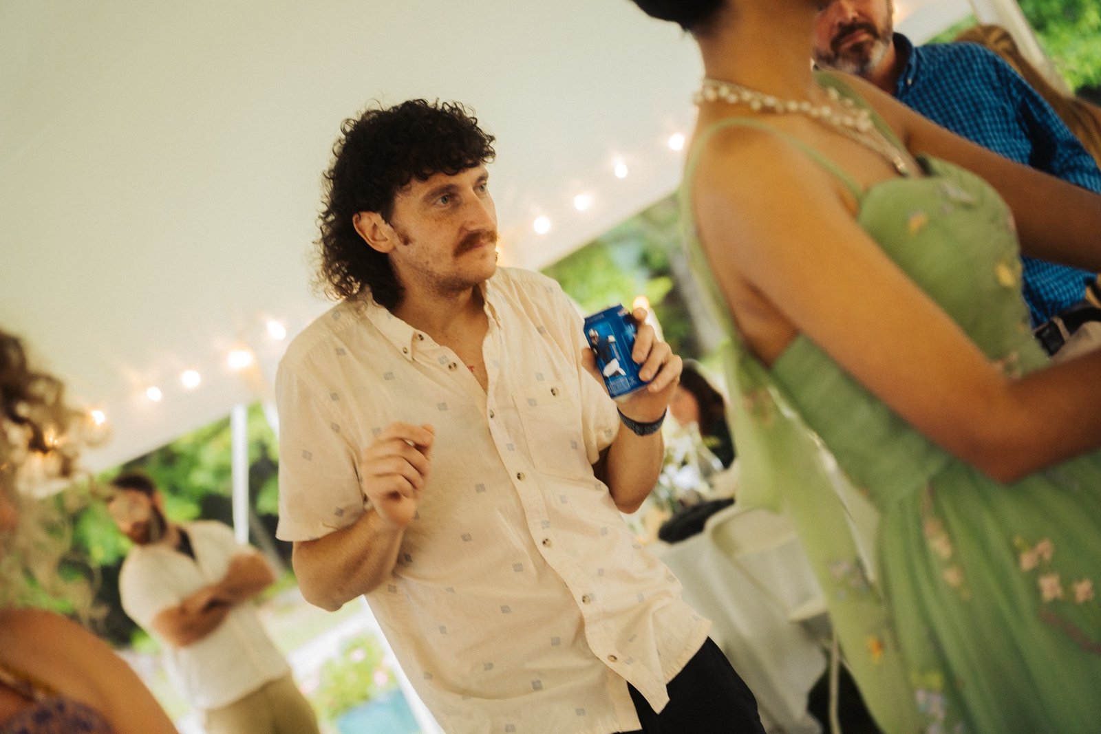 A wedding guest dancing under string lights inside the reception tent