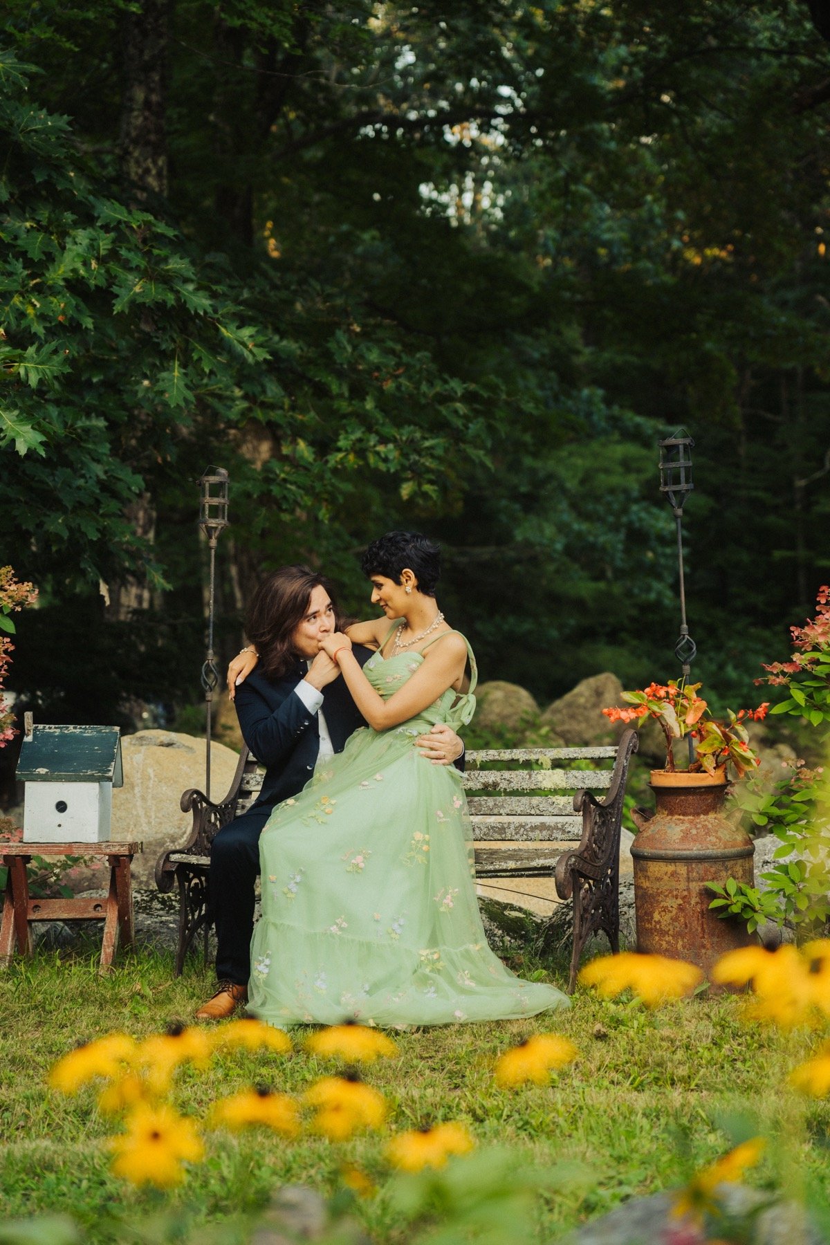 Bride in a pale green gown and groom standing back to back among tall forest trees