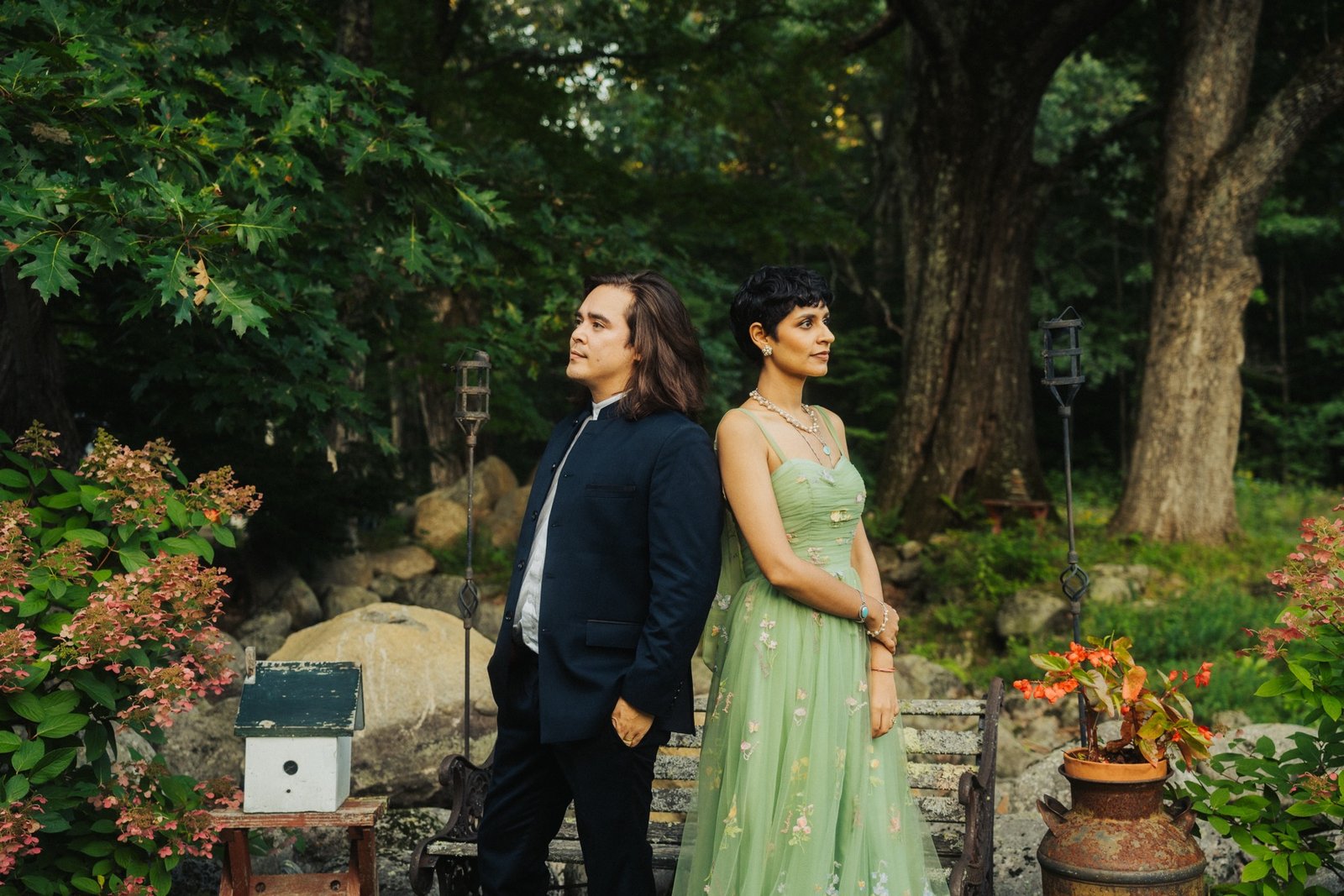 Bride and groom seated together on a garden bench, groom kissing the bride's hand