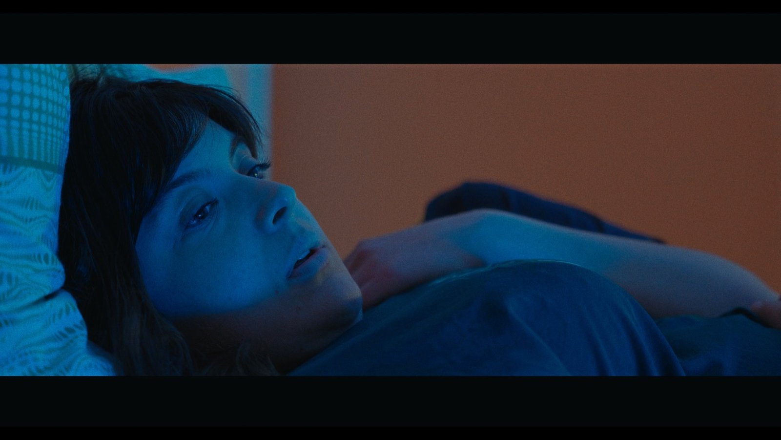 FONDENTE — a character lying down in blue-lit interior light