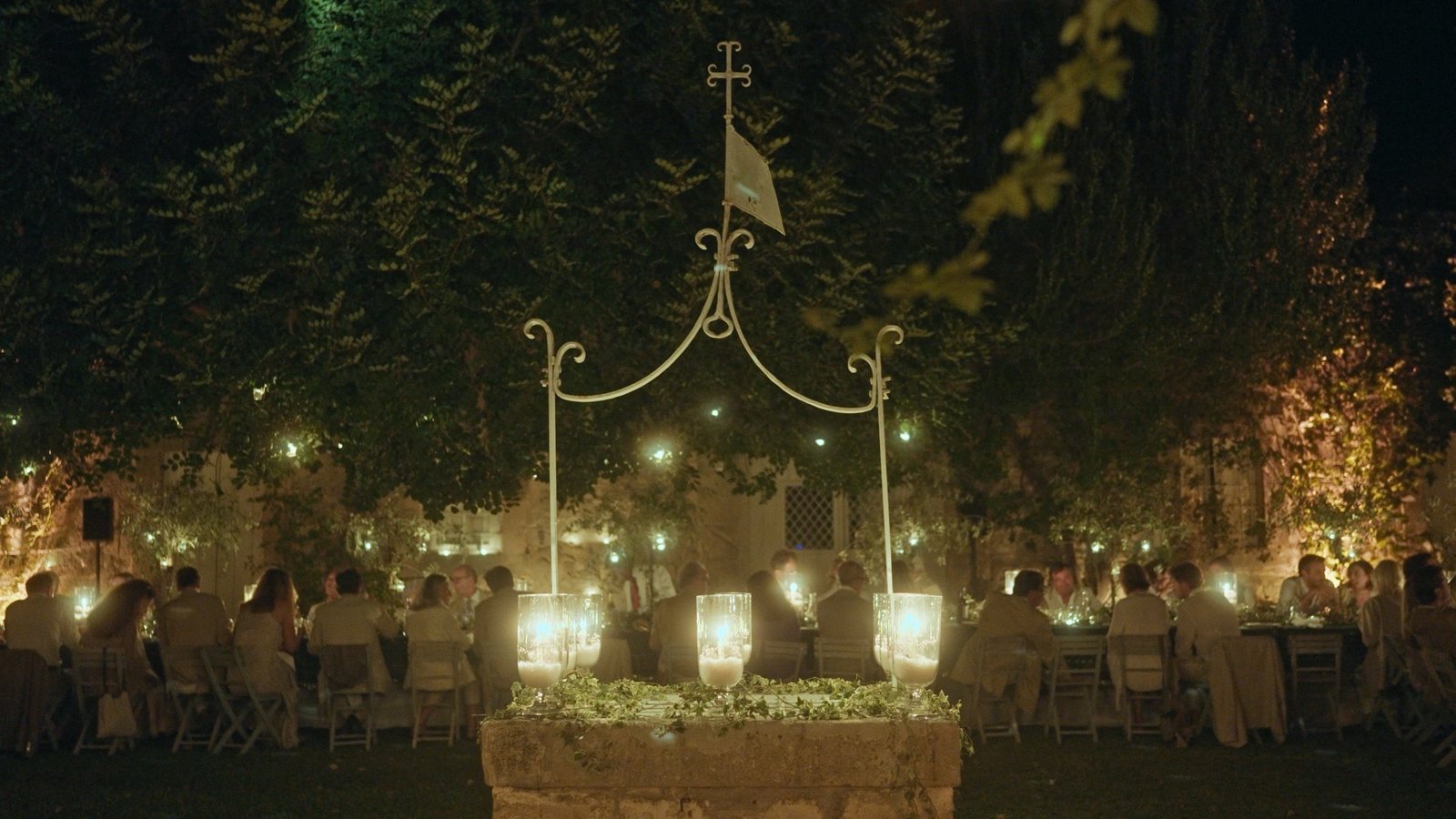 Candlelit wedding dinner under a decorated arch in a Sicilian garden at night, from Lucrezia and Giulio's destination wedding filmed by Francesco La Rosa, 2023
